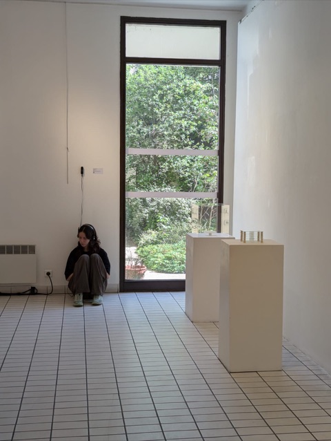 Lola Le Vient assise au sol, un casque sur les oreilles, dans l’exposition J’ai confondu le sol et les nuages