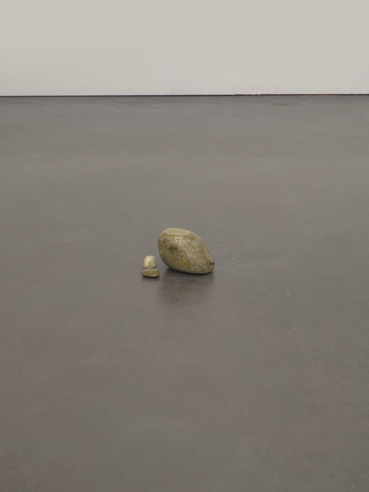 Deux cailloux posés au sol dans une salle d’exposition